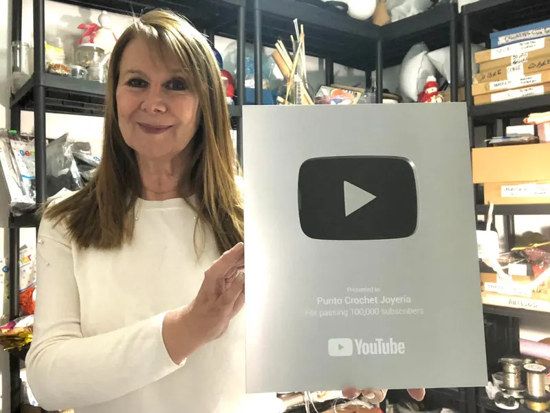 Adriana Laura Méndez sostiene la placa de plata de YouTube por 100.000 suscriptores