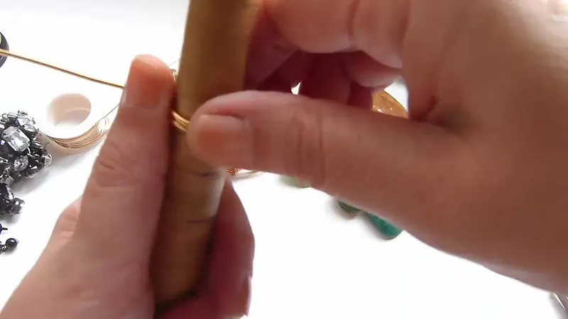 Manos que cruzan el alambre grueso alrededor del mandril de anillos