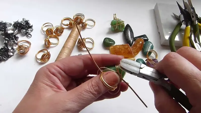 Pinza que aprieta las vueltas de alambre alrededor de una gema verde