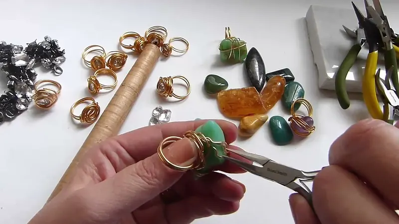 Pinza de punta redonda que ajusta las vueltas de alambre sobre una gema verde