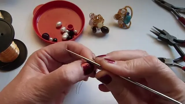 Aguja de crochet con el alambre montado, entre las dos manos, al comenzar el primer punto