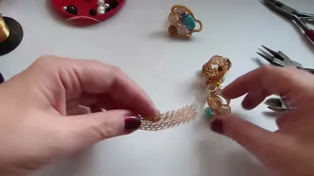 Tira de malla plana de alambre dorado sostenida entre los dedos para ver el largo