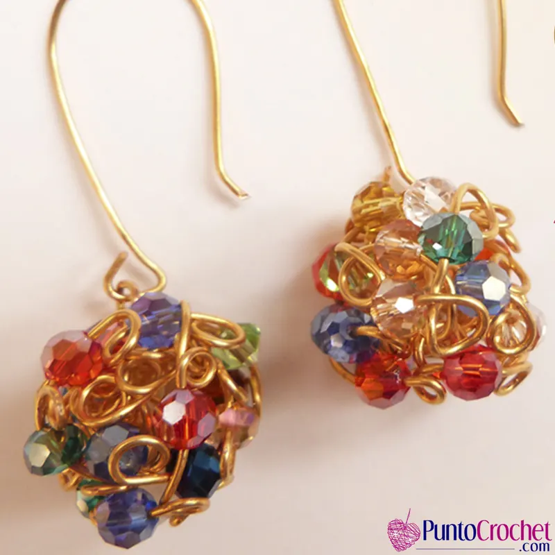 Dos aretes con gancho dorado y una esfera de alambre dorado en aros con cristales facetados de colores