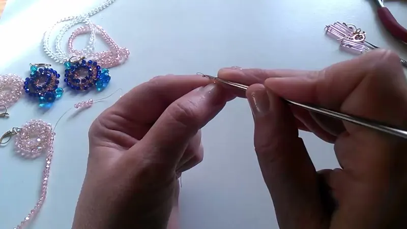 Las manos tejiendo la cadeneta con la aguja de crochet y el alambre fino