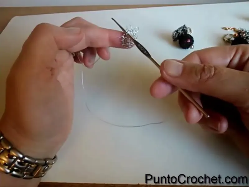 La aguja de crochet tomando puntos muy sueltos en el borde de la rueda de alambre