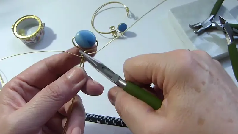 Pinza plana que ajusta las vueltas de la tira fina debajo de la gema azul
