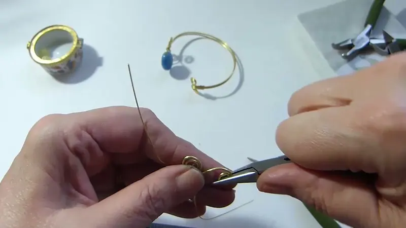 Manos que enrollan un espiral con la pinza de punta redonda