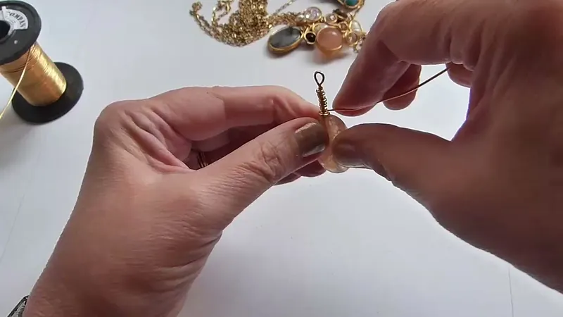 La piedra ovalada sujeta con el alambre que rodea el costado, con el aro y el bastón arriba