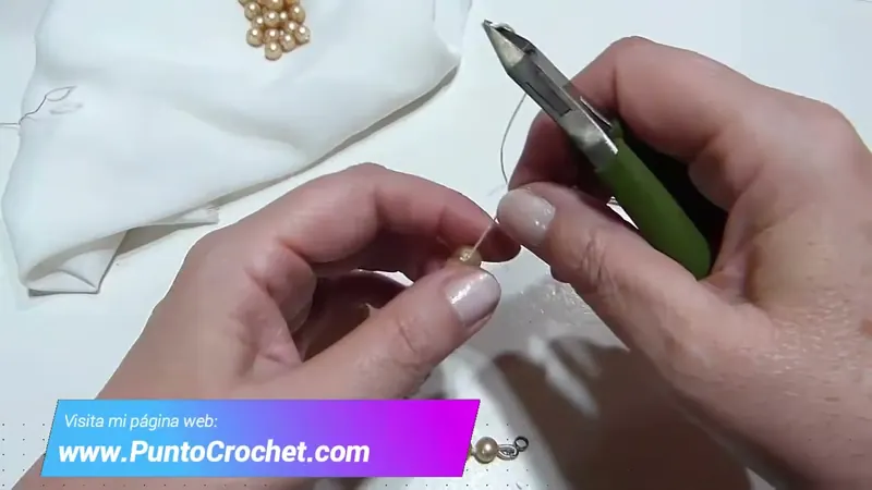 La pinza de corte cortando el hilo al ras junto a la última perla