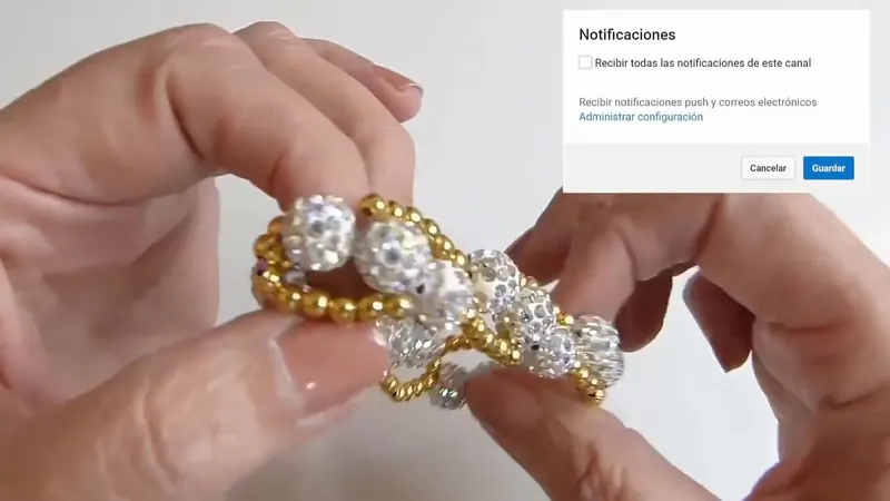 Mano con un brazalete elástico de bolitas doradas y bolas brillantes blancas