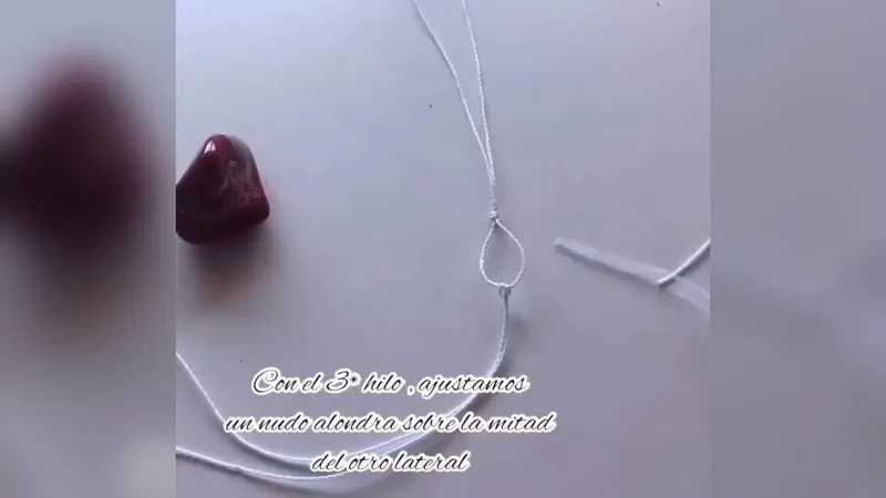 Un aro de hilo con nudo, junto a la gema, y el cartel del tercer hilo