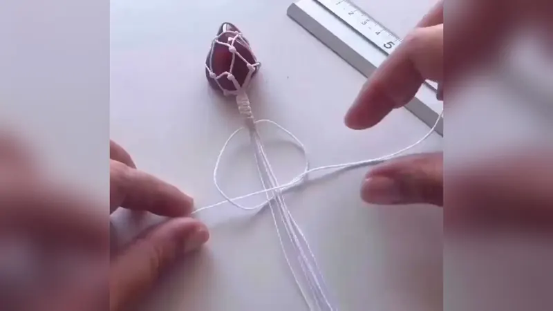 La gema en su red, con un tallo de nudos planos y varios hilos colgando, al lado de una regla