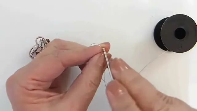 Aguja de crochet y alambre con el aro de inicio sujeto con el pulgar y el índice