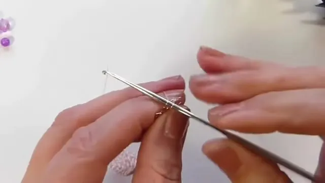 Aguja de crochet entrando en un punto bajo de la malla de oro rosa