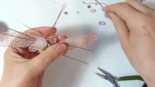 Gemas rosadas y cristales sujetos con alambre sobre el centro de la malla, entre los dedos