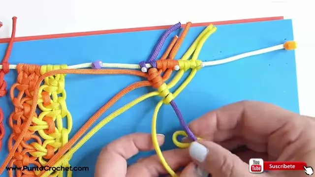 Cordones naranja y amarillo con una guía lila que marca la diagonal, y una mano pasando una lazada