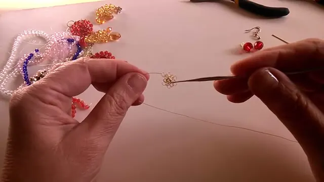 Flor de alambre con la vuelta de punto peruano tejida, sostenida con una mano y la aguja de crochet en la otra