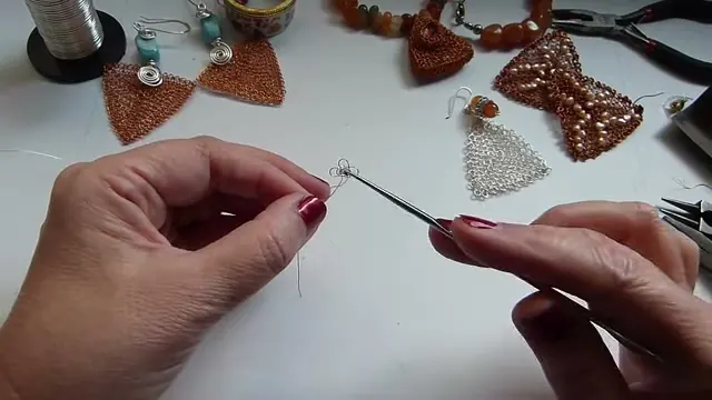 La aguja de crochet trabajando el aro pequeño de alambre que forma la base del triángulo