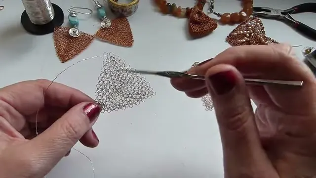 Adriana sostiene el triángulo de malla ya formado con una mano y la aguja de crochet en la otra