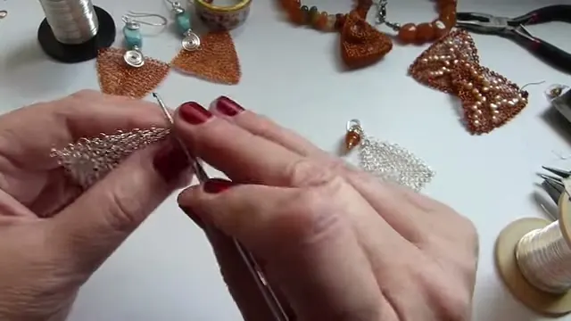 La aguja de crochet pasando el repaso por los puntos del borde del triángulo