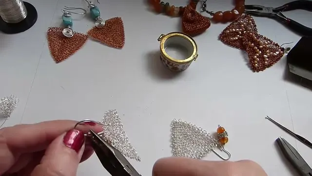 La pinza dando forma al gancho, con el otro pendiente ya armado sobre la mesa