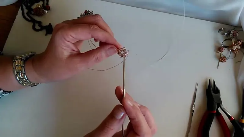 Disco pequeño de tejido de alambre montado en la aguja de crochet, sostenido con los dedos