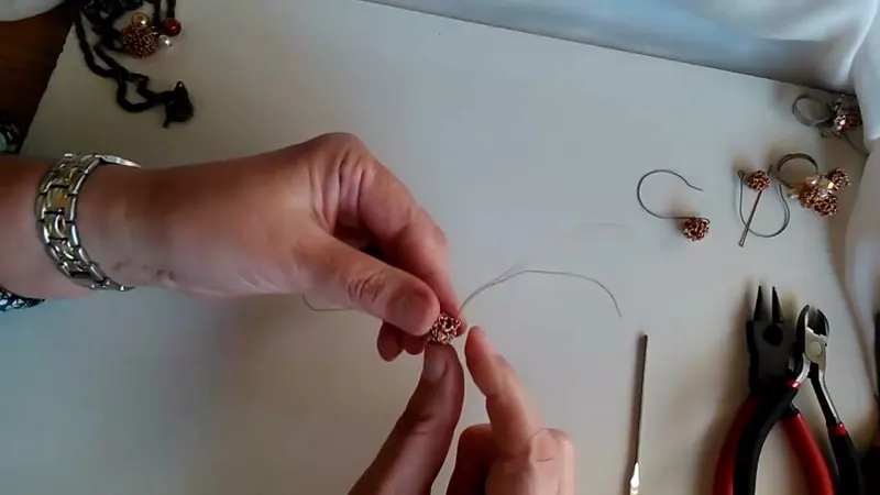 Esfera de alambre casi cerrada, sostenida con una mano, con los extremos de alambre a la vista
