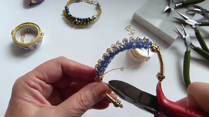 El alicate rojo cortando el alambre sobrante en un extremo de la pulsera