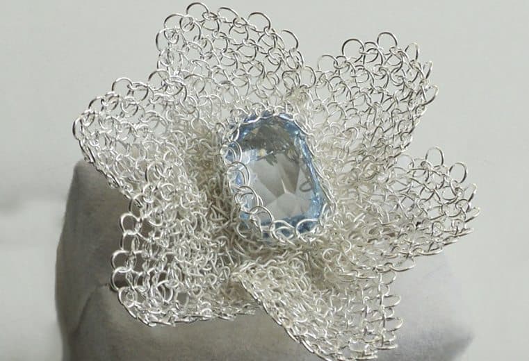 anillo con forma de flor tejido a mano con alambre de plata y cristal celeste facetado